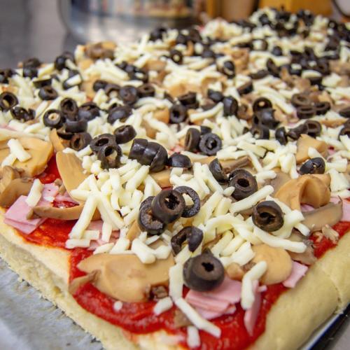 La pizza à la sauce tomate, jambon, champignons, mozzarella et olives noires